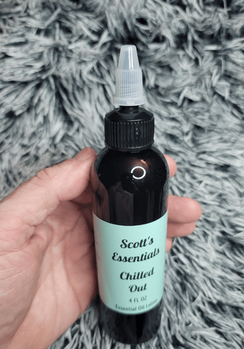 Bottle of 'Scott's Essentials Chilled Out' essential oil blend held by a hand with easy twist open lid