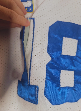 Close-up of a sports jersey with number 18 being adjusted by a hand.