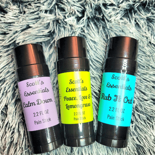 Three Scott's Essentials pain stick containers on a textured surface