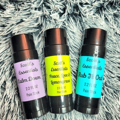 Three Scott's Essentials pain stick containers on a textured surface