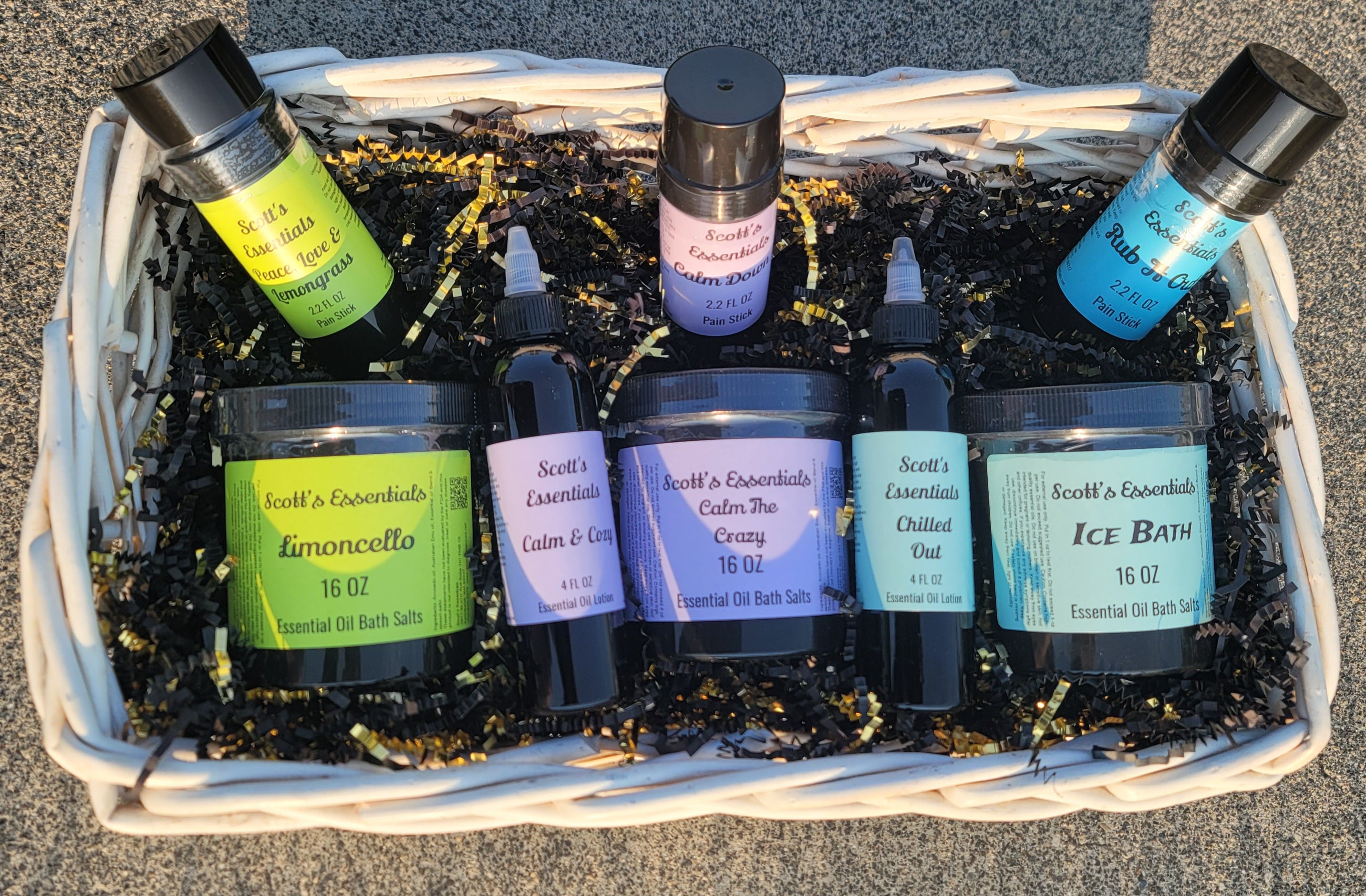 Basket with essential oil products including lotions, bath salts and twist-up sticks on a textured surface.