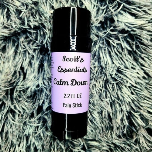 Pain stick labeled 'Scott's Essentials Calm Down' on a textured surface
