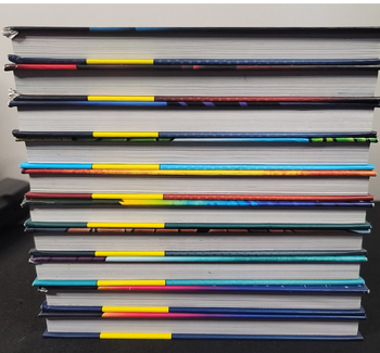 Stack of Dog Man used hardcover books with different colored spines on a black background