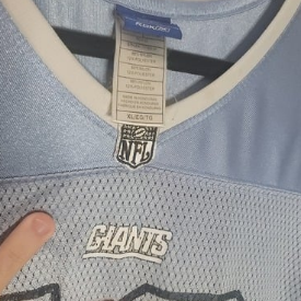 Close-up of a Eli Manning jersey with 'NFL' and 'Giants' branding, featuring a tag.