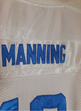 White sports jersey with blue stitched text 'MANNING' on a close-up view