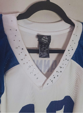 White Peyton Manning jersey blue accents and rhinestone details on a hanger with a visible tag.