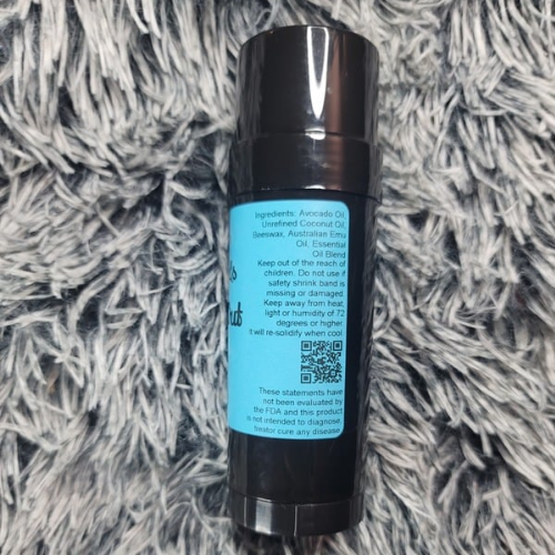 Rub It Out pain stick bottle with blue label on a textured gray surface