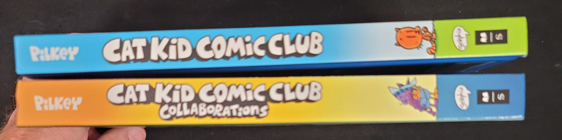 Two books from the Cat Kid Comic Club series held together on a black background